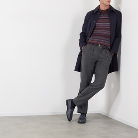 Model wearing Dolce & Gabbana blue wool polo with burgundy stripe detail, styled with navy overcoat and grey trousers.