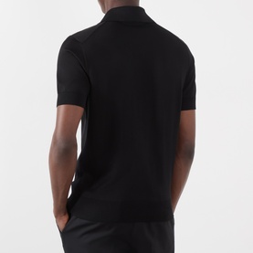 Model wearing Dolce & Gabbana black silk polo shirt, rear view showing short sleeves and ribbed collar.