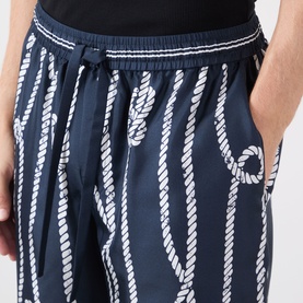 Model wearing Dolce & Gabbana navy silk shorts with all-over white rope print, elasticated drawstring waistband, side pockets visible.