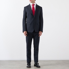 Model wearing Dolce & Gabbana black wool suit with red tie and white shirt, styled with black leather Oxford shoes.