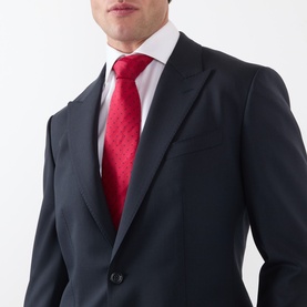 Model wearing Dolce & Gabbana black slim-fit suit, styled with white shirt and red patterned tie, single-button detail visible.