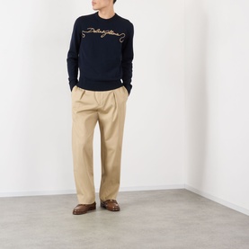 Model wearing Dolce & Gabbana dark blue wool sweatshirt with script logo, styled with beige wide-leg trousers and brown loafers.
