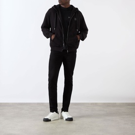 Model wearing Dolce & Gabbana black Logo Plate Hoodie with zip fastening, styled with black jeans and white trainers.