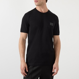Model wearing Dolce & Gabbana Logo Badge T-Shirt in black cotton with round neckline and small logo badge at chest
