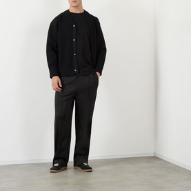 Model wearing Dolce & Gabbana black Logo Badge T-Shirt, styled with black button cardigan and straight-leg trousers.