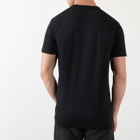 Model wearing Dolce & Gabbana Script Logo T-Shirt in black, rear view, round neckline, short sleeves, straight hem, styled with grey trousers