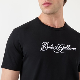 Model wearing Dolce & Gabbana Script Logo T-Shirt in black, with white script logo detail at chest, round neckline, short sleeves.