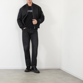 Model wearing Dolce & Gabbana black Script Logo T-Shirt with black bomber jacket, dark jeans, and black boots.