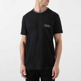 Model wearing Dolce & Gabbana black cotton T-shirt with tipped crew neck and small logo patch on chest.