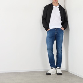 Model wearing Dolce & Gabbana Optical White Tipped Logo T-Shirt with black bomber jacket, blue slim jeans and white trainers.