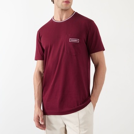 Model wearing Dolce & Gabbana Bordeaux Tipped Logo T-Shirt with round neck, tipped detail, and chest logo badge. Styled with cream trousers.