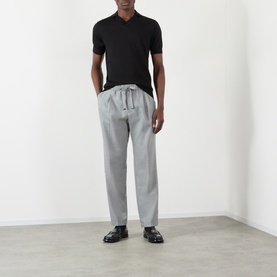 Model wearing Dolce & Gabbana Grey Melange virgin wool trousers with drawstring waist, styled with black polo shirt and black loafers.