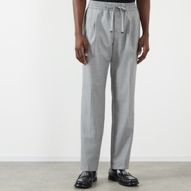 Model wearing Dolce & Gabbana grey melange wool drawstring trousers with front pleats, styled with black loafers.