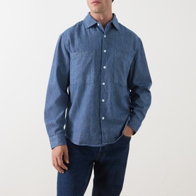 Model wearing Farah Vintage Mid Indigo casual shirt in denim cotton, featuring chest pockets and long sleeves, styled with blue jeans
