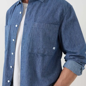 Model wearing Farah Vintage Mid Indigo casual shirt, 100% cotton with chest patch pocket and white buttons, styled with grey crew-neck tee