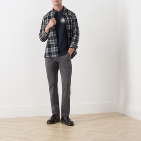 Model wearing Farah Vintage Charcoal Chinos with a navy graphic tee, plaid overshirt, and black leather shoes.