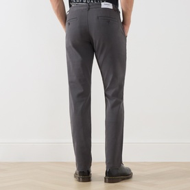 Model wearing Farah Vintage Charcoal Chino trousers, rear view, styled with a graphic tee and brown boots.