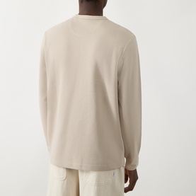 Model wearing Farah Vintage Putty Crew Neck T-Shirt, long-sleeve cotton style, back view, styled with cream trousers.