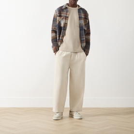 Model wearing Farah Vintage Putty Crew Neck T-shirt, styled with brown plaid overshirt, cream wide-leg trousers and white trainers.