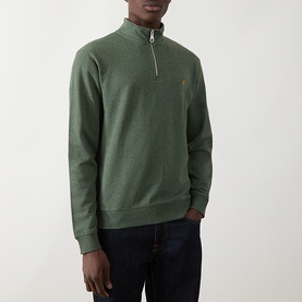 Model wearing Farah Vintage Half Zip sweatshirt in Rosemary Marl green, with gold logo, styled with dark denim jeans.