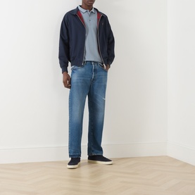 Model wearing Farah Vintage Icelandic Blue cotton polo, styled with navy zip-up jacket, mid-blue straight-leg jeans and dark trainers.