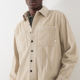 Model wearing Farah Vintage putty corduroy casual shirt with chest pockets and dark buttons, styled over a green layer.