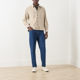 Model wearing Farah Vintage Putty cotton zip-through casual shirt with blue jeans and white trainers.