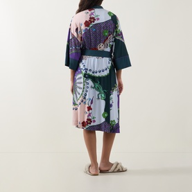Model wearing Mey Mystic Jade Kimono in modal, rear view, floral and peacock print with teal belt, styled with white sliders.