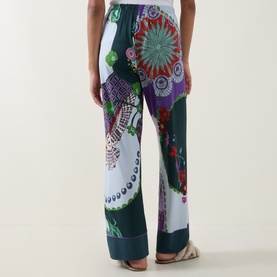 Model wearing Mey PJ Pants in Mystic Jade with multicolour mandala print, wide-leg silhouette, styled with nude strappy sandals.
