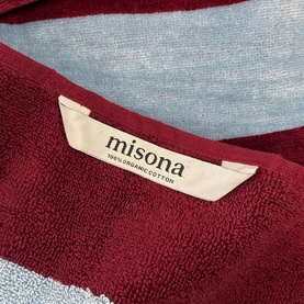 Misona Beach Towel Red Sky in red and sky blue, 100% organic cotton, close-up of woven label and jacquard texture detail.
