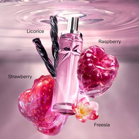 Mugler body mist in pink bottle surrounded by labelled fragrance notes: strawberry, raspberry, licorice, and freesia on pink background.