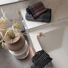 Odyssey Carnival Towel Black, 100% cotton jacquard beach towel in black with multicolour stripe pattern, styled in bathroom setting