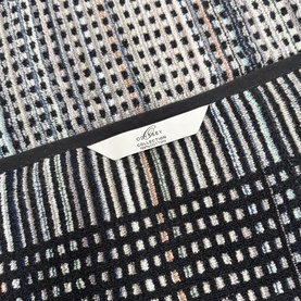Odyssey Carnival Towel in black, 100% cotton jacquard weave with multicolour geometric dot and stripe pattern, label visible.