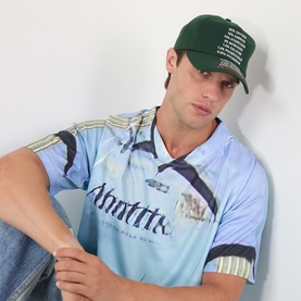 Model with Pleasures Atmosphere Logo Baseball Cap in Forest, embroidered logo detail, paired with light blue sports jersey
