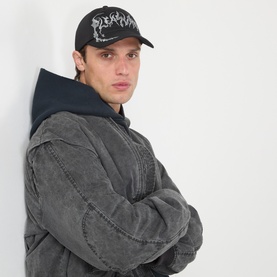 Model with Pleasures Claws Logo Baseball Cap in black, six-panel design with claw embroidery, worn with grey washed hoodie jacket