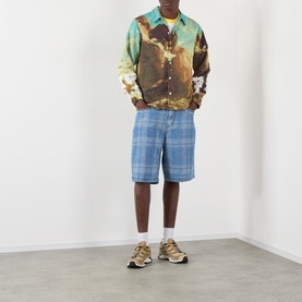Model wearing Pleasures multi-coloured tie-dye casual jacket, styled with blue plaid shorts, white socks and chunky trainers
