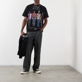 Model wearing Pleasures Creatures of Love Logo Graphic T-Shirt in black with grey wide-leg trousers and black high-top trainers.
