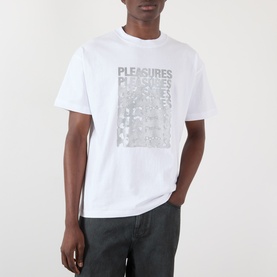 Model wearing Pleasures Immolate Logo Graphic T-Shirt in white with faded repeat graphic print, styled with dark grey trousers.