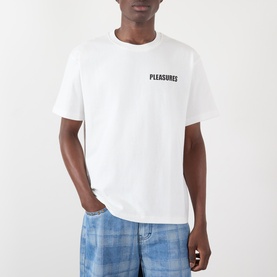 Model wearing Pleasures Impact Logo Graphic T-Shirt in white with chest logo print, styled with blue check trousers.