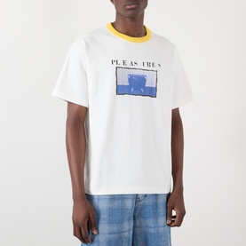 Model wearing Pleasures Speaking Logo Graphic T-Shirt in white with yellow contrast collar and blue graphic print, styled with light wash jeans.