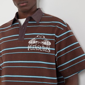 Model wearing Pleasures brown striped polo shirt with blue stripes, chest pocket, and embroidered graphic logo detail
