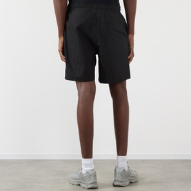 Model wearing Pleasures Active Striped Shorts in black with elasticated waist, styled with white socks and grey trainers.