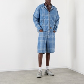 Model wearing Pleasures blue plaid shorts, styled with matching zip-up hoodie jacket, patterned scarf and grey trainers.
