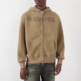 Model wearing Pleasures Zine Logo Zip Hoodie in beige with embossed logo, fleece-lined, styled with distressed jeans