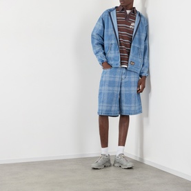 Model wearing Pleasures Logo Check Denim Zip Hoodie in blue, styled with matching check shorts, brown top and grey trainers.
