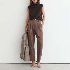 Model wearing Reiss chocolate brown high-waist tailored trousers with belt, styled with brown sleeveless top, carrying checked blazer