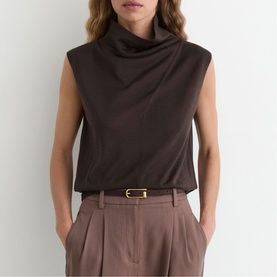 Model wearing Reiss chocolate brown sleeveless cowl neck top, styled with taupe wide-leg trousers and a gold-buckle belt.