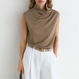 Model wearing Reiss khaki green sleeveless draped neck top, styled with white wide-leg trousers and a tan leather belt.