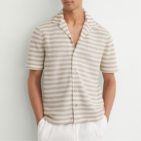 Model wearing Reiss white striped short-sleeve camp collar shirt, styled with white trousers