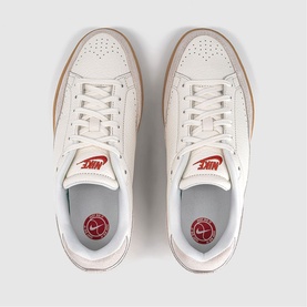 Nike trainer in sail white leather, overhead flat lay showing gum sole, red Nike branding on tongue and insole